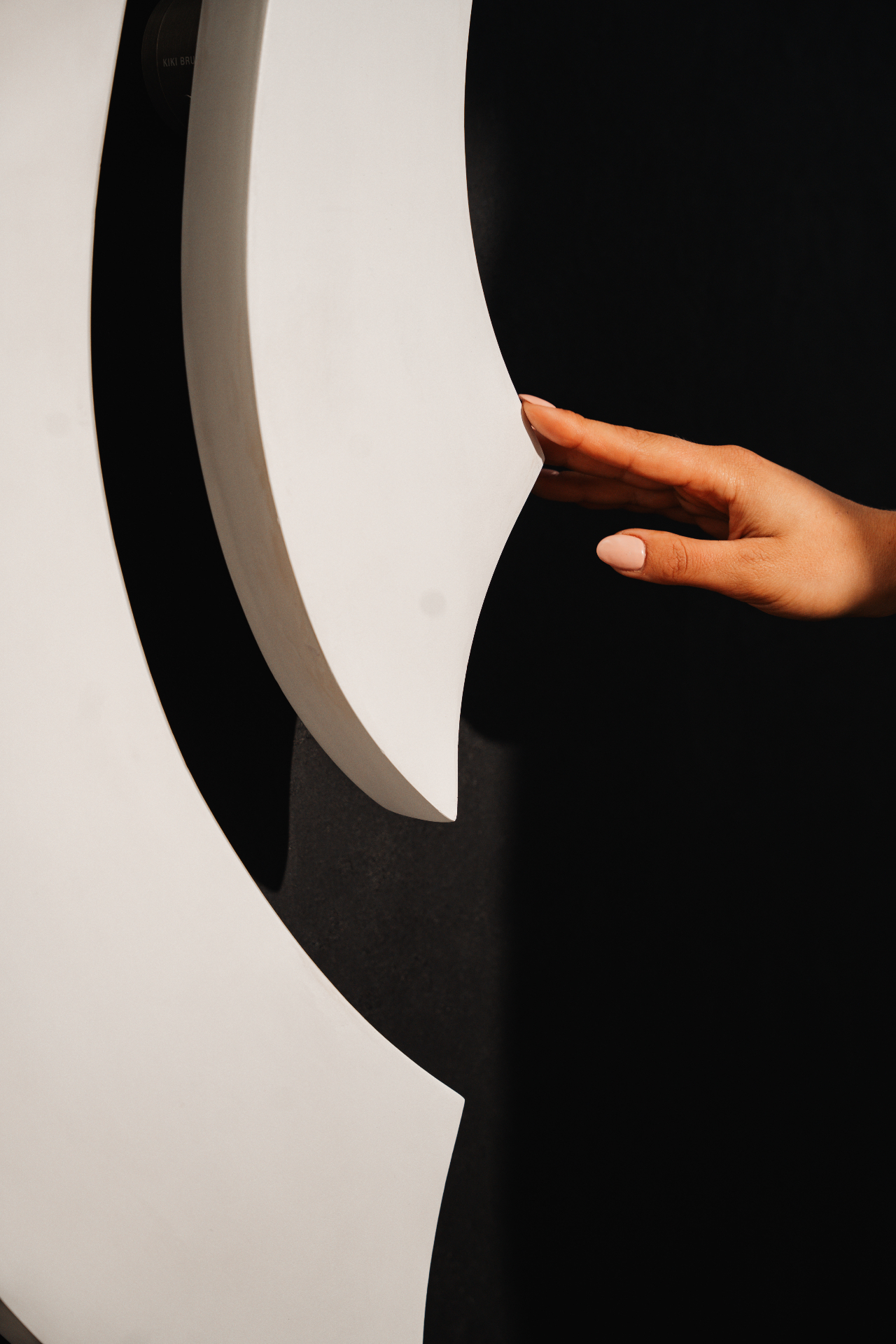 Hand resting against a sculptural stucco form by Kiki Brusché